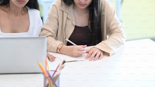 Two young woman designer in casual wear working on new project together with computer laptop at creative office.