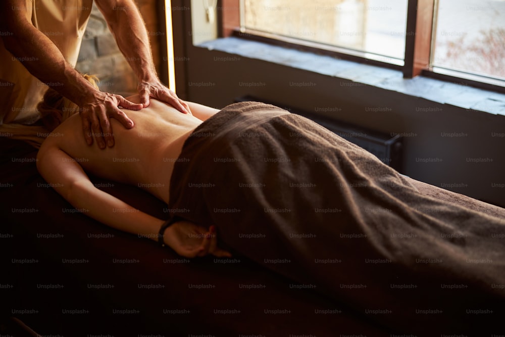 Foto do espaço de cópia da pessoa coberta com toalha deitada na mesa de massagem enquanto recebe tratamento