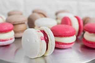 Close up de sobremesa colorida de macarons de chocolate branco, vermelho e caramelo, recheio com ganache saborosa, na mesa da cozinha leve ou confeitaria.