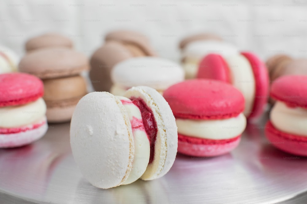 Close up of colorful white, red, and caramel chocolate macarons dessert, filling with tasty ganache, on the table at light kitchen or confectionery shop.