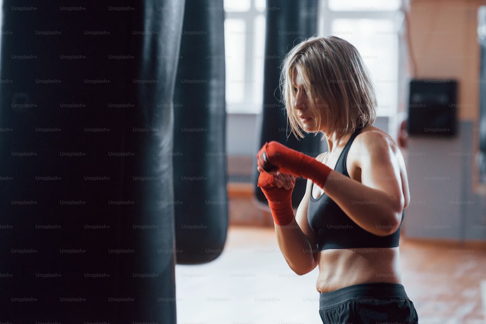 That girl can beat some people. Female boxer is punching the bag. Blonde have exercise in the gym.