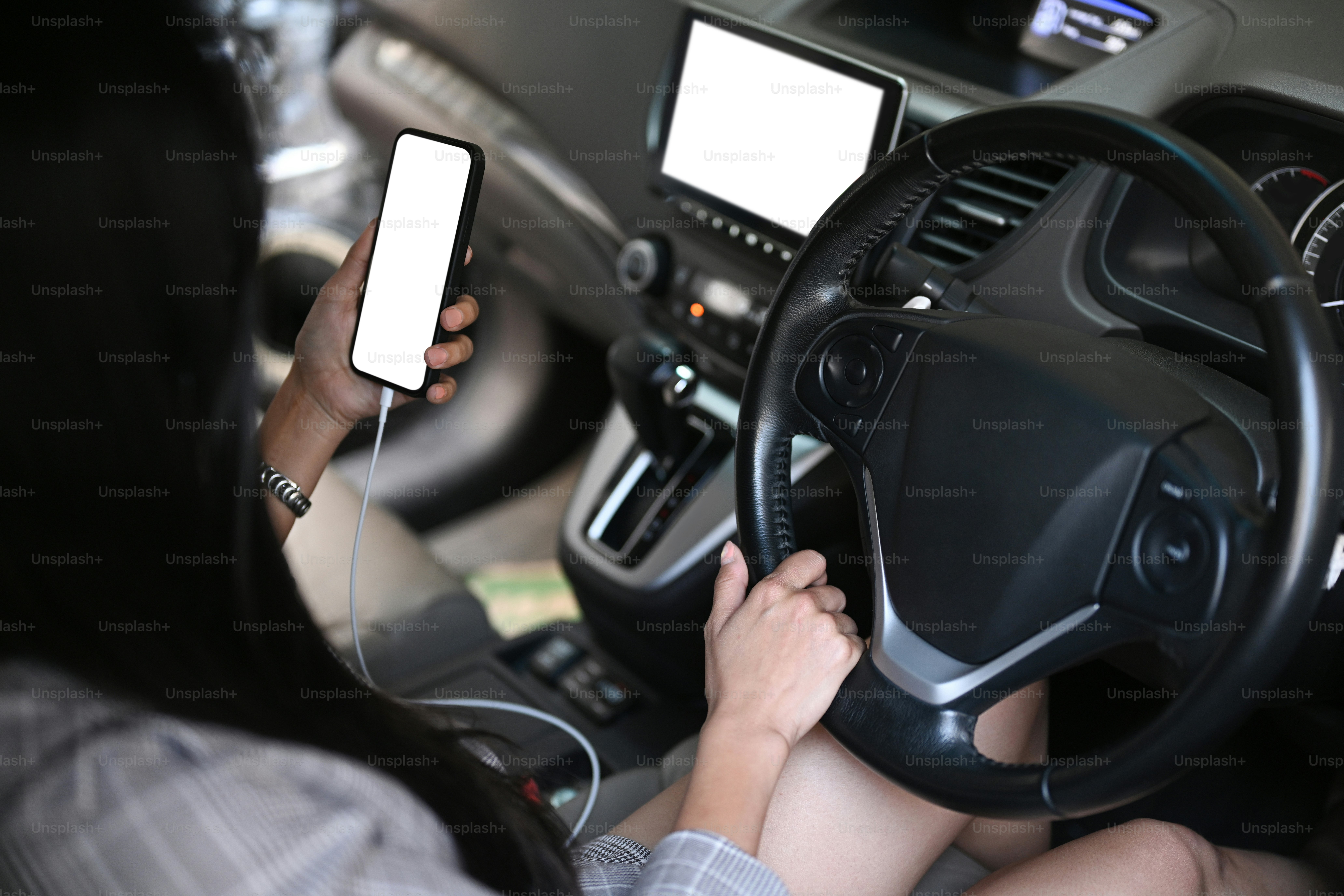 Young businesswoman sitting in car and using mobile phone.