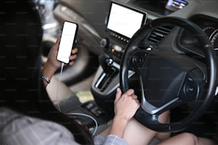 Young businesswoman sitting in car and using mobile phone.