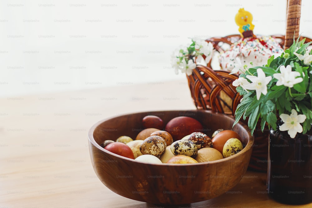 Oeufs teints naturels modernes, pain de Pâques fait maison dans un panier en osier, lapin et fleurs printanières épanouies sur une table rustique. Joyeuses Pâques. Nourriture traditionnelle de Pâques pour la bénédiction de l’église et le dîner de fête
