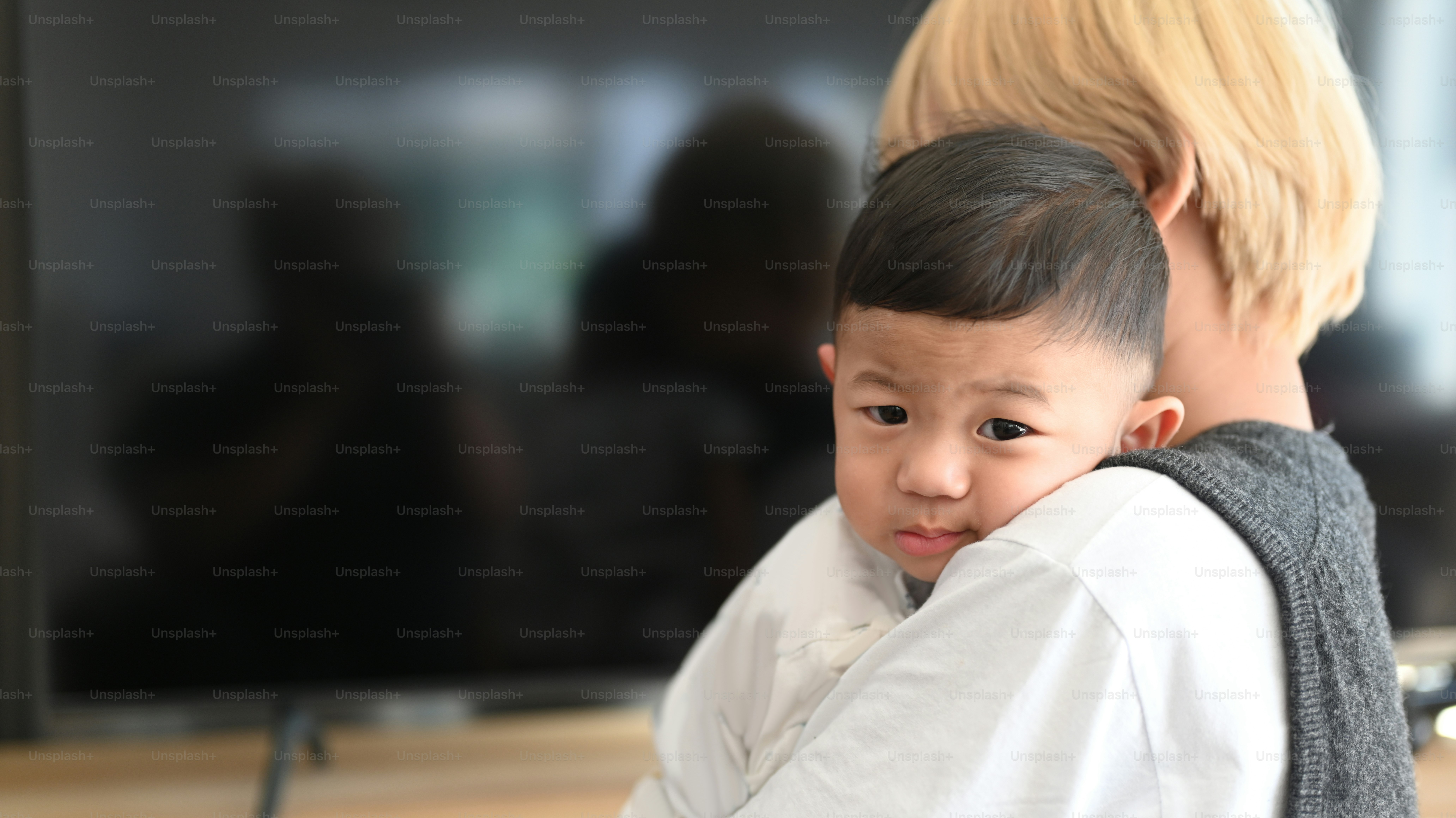 Asian mother holding her baby standing in living room at home.
