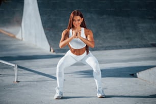 Shot of sportive woman doing fitness exercises near the lake at daytime.