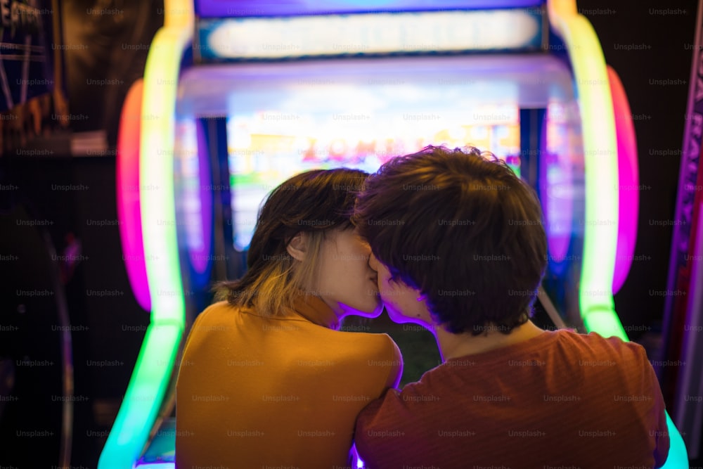 Casal se divertindo na sala de jogos. Jogando um jogo. O casal está se beijando.