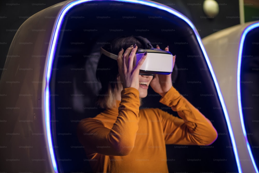 Mujer joven en sala de juegos con casco de realidad virtual.