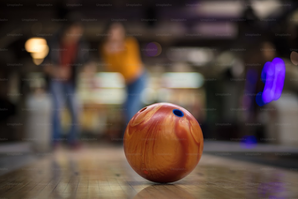 Jeune couple s’amusant dans une salle de bowling.  L’accent est mis sur le lanceur.