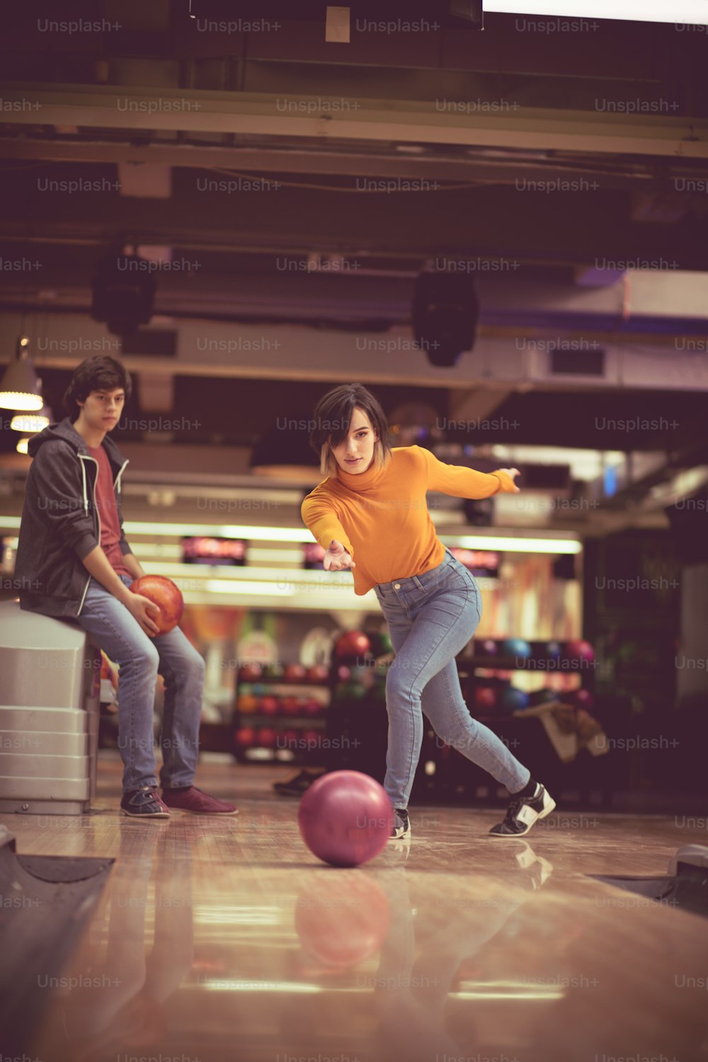 Couple in bowling alley. Woman throws a bowling ball.