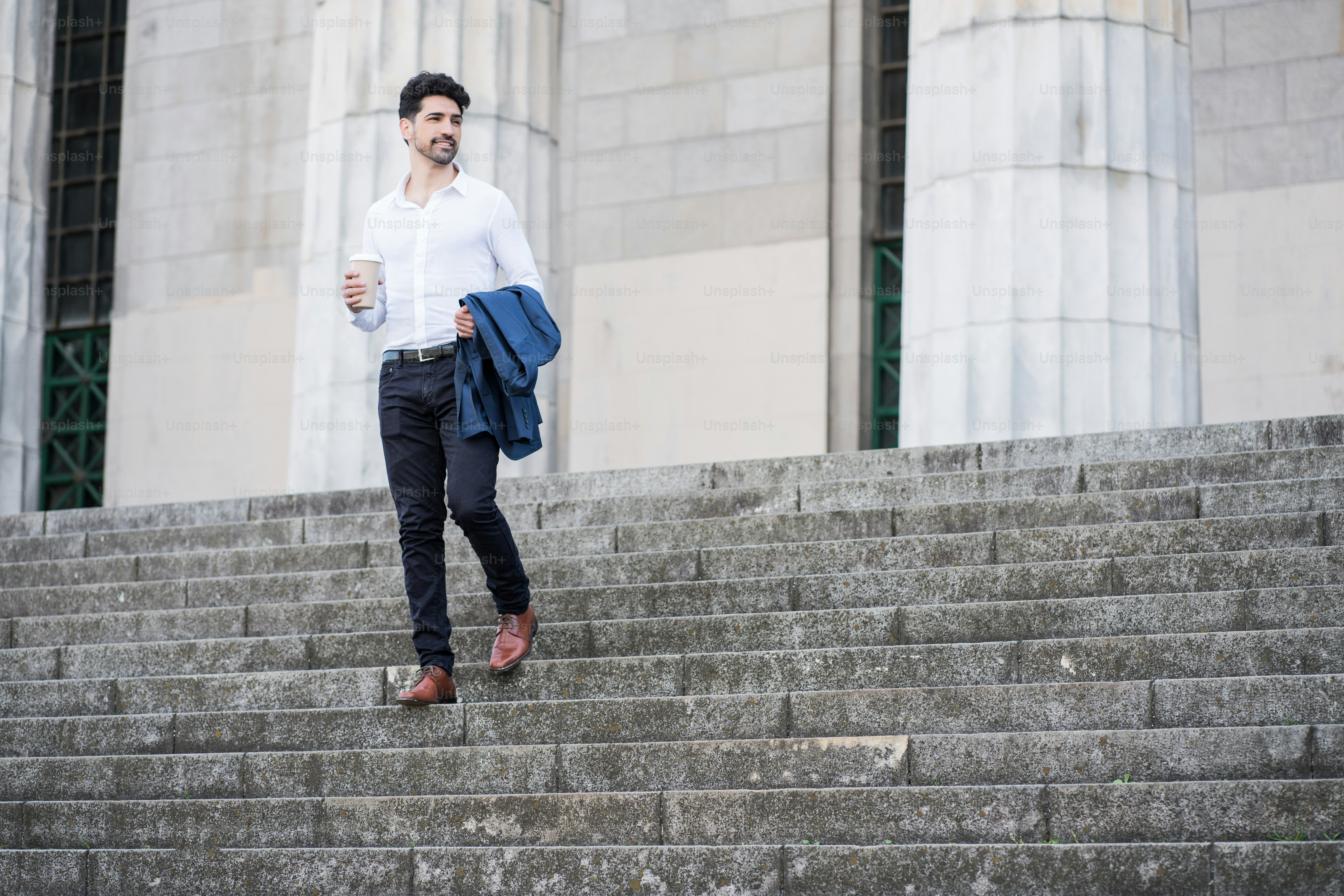 Porträt eines Geschäftsmannes mit einer Tasse Kaffee auf dem Weg zur Arbeit im Freien. Geschäftskonzept.