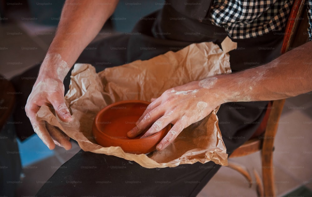 陶芸家のクローズアップ写真は、紙に彼の新鮮な製品をパッケージします。