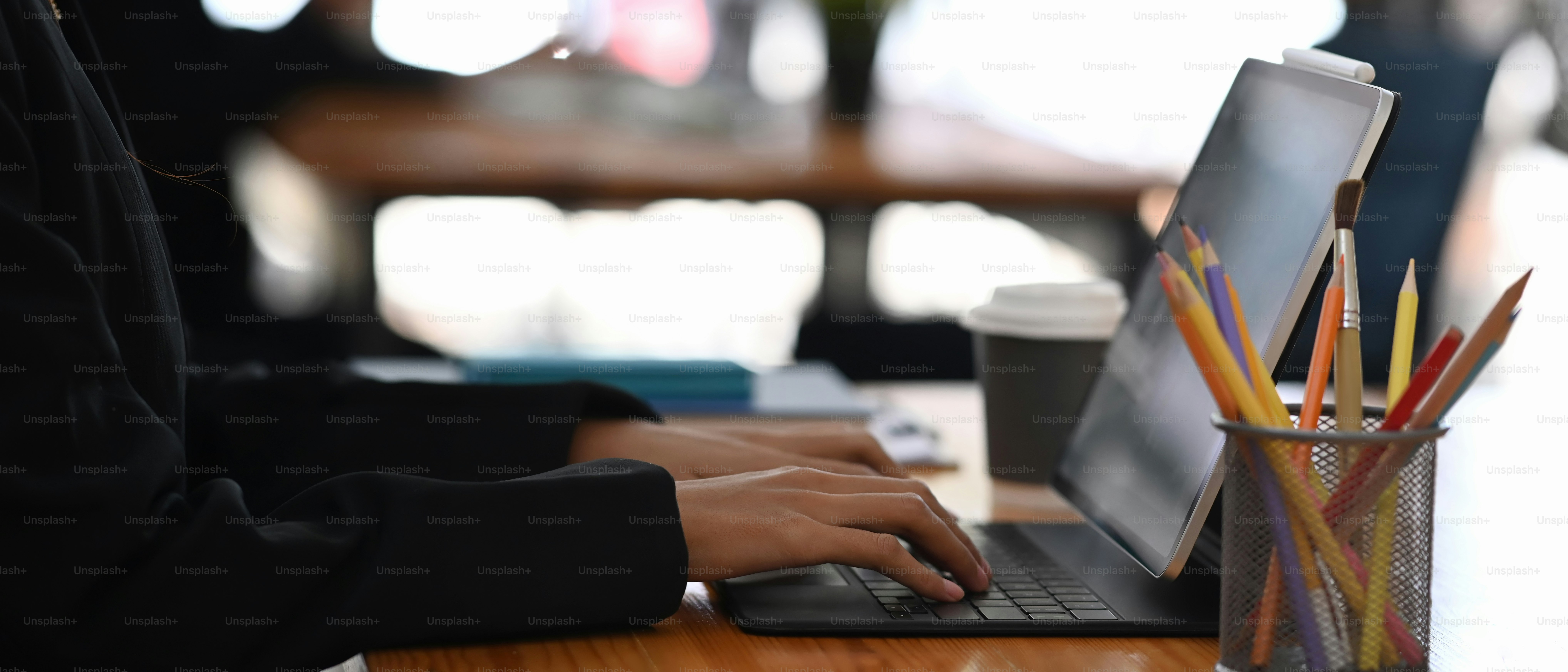 Foto horizontal de mãos de empresária digitando no teclado sem fio do tablet digital.