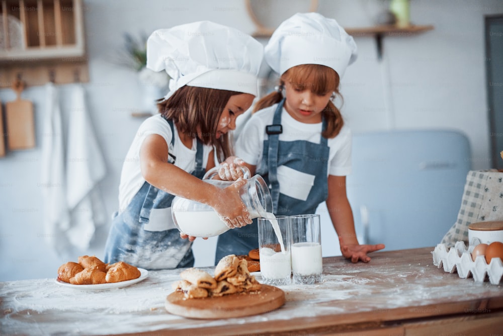 Las galletas están listas. Niños de la familia con uniforme de chef blanco preparando comida en la cocina.