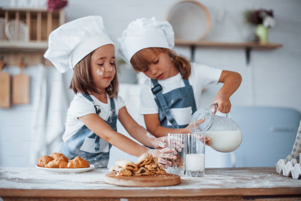 Cookies est prêt. Des enfants de la famille en uniforme de chef blanc préparent de la nourriture dans la cuisine.