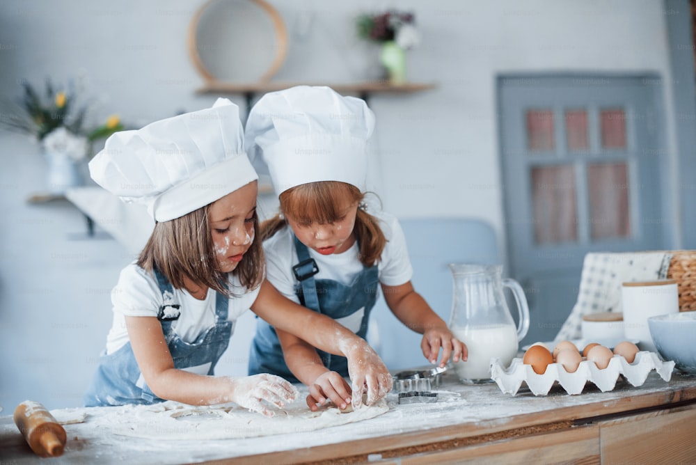 요리에 집중. 부엌에서 음식을 준비하는 흰색 요리사 유니폼을 입은 가족 아이들.