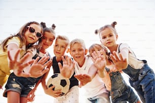 Hallo, Geste. Mit Fußball. Porträt von Kindern, die zusammenstehen und für die Kamera posieren.