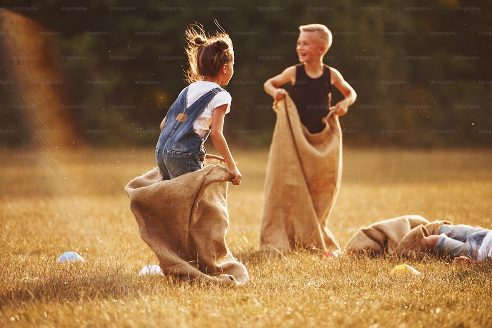 Jumping sack race outdoors in the field. Kids have fun at sunny daytime.