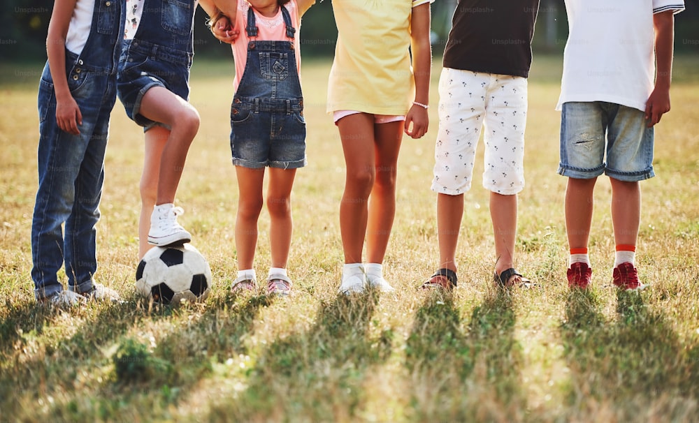 Vue particulaire d’enfants sportifs avec un ballon de football se tient ensemble sur le terrain par une journée ensoleillée.