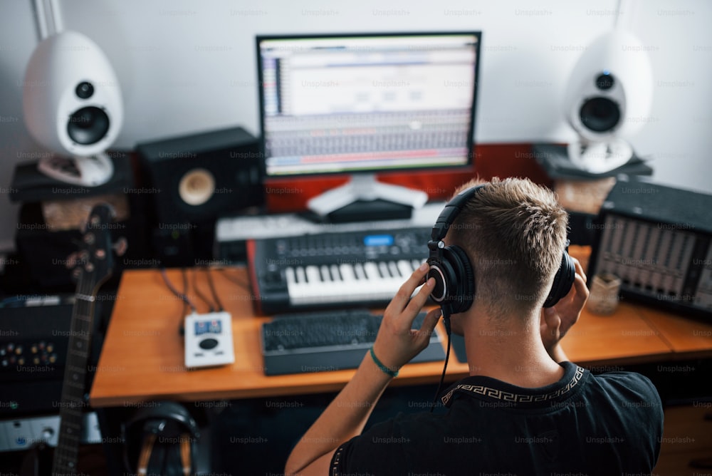 음악 듣기. 헤드폰을 착용한 사운드 엔지니어가 스튜디오에서 실내에서 작업하고 믹싱합니다.