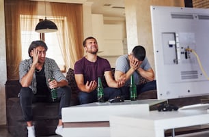 Es una derrota. Triste tres amigos viendo fútbol en la televisión juntos en casa.