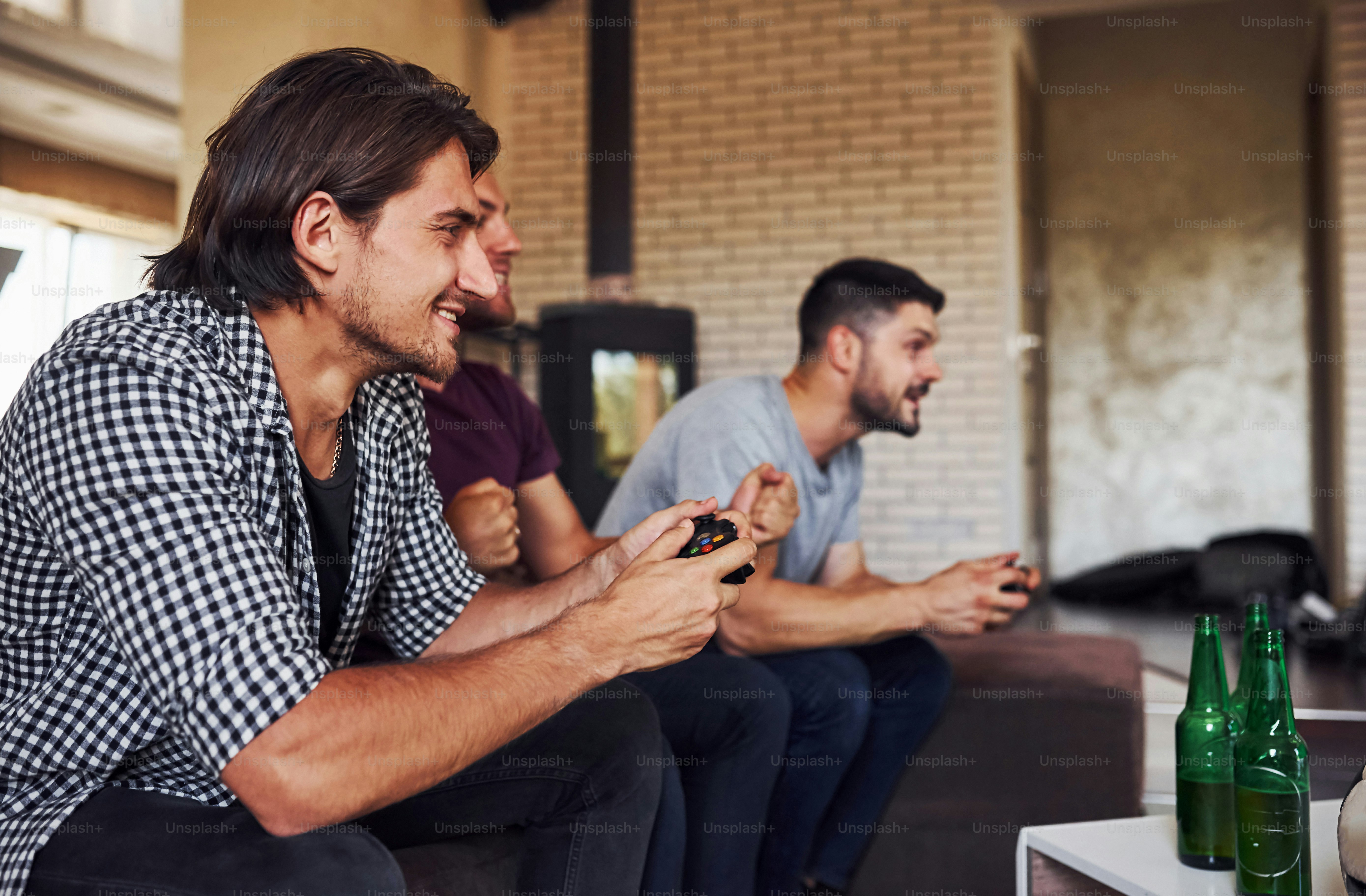 Side view. Group of friends have fun playing console game indoors at living room.