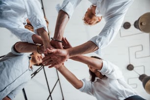 View from below. Successful business people putting their hands together.