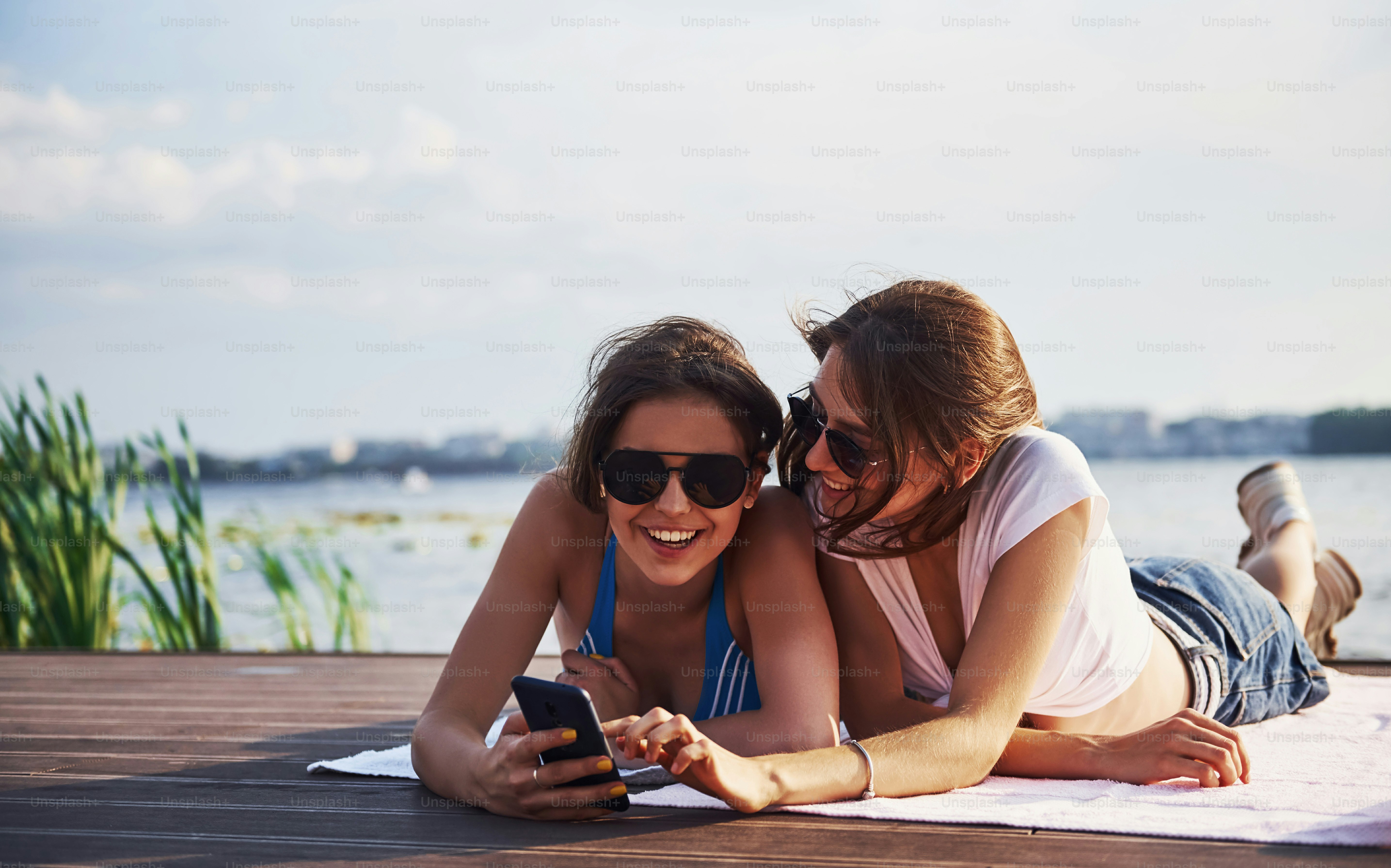 Two girls on the beach lying down on the ground and enjoying warm sunlight.