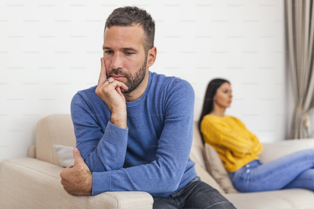 Young couple sitting on sofa being angry after fight. Couple Having Argument At Home. Girlfriend and boyfriend sitting next to each other angry, couple fighting
