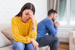 Unhappy thoughtful married couple spouses sitting separately on couch at home, wife husband not talking ignoring each other having problems in relationships, break up and divorce concept.