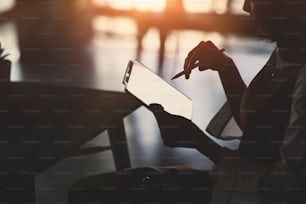 Silhouette de femme d’affaires assise dans un bureau et tenant une tablette numérique.