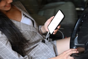 Young businesswoman holding smart phone while driving car.