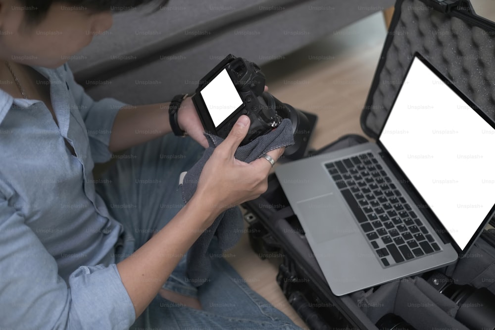 Fotógrafo usando una computadora portátil y verificando la configuración de su cámara antes de disparar.