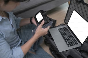 Photographer using computer laptop and checking his camera setting before shooting.