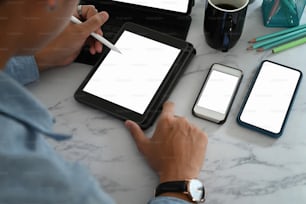 Homem de negócios que trabalha on-line com vários dispositivos na mesa de mármore.