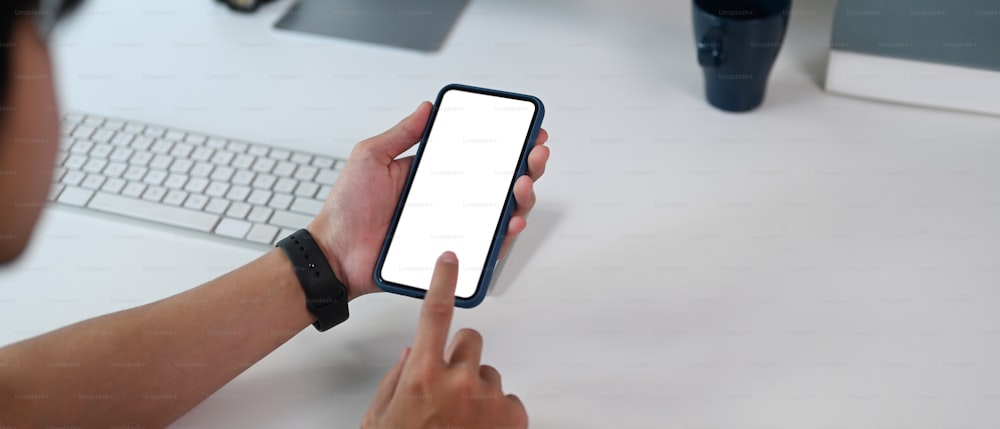 Horizontal photo of man using smart phone during working at his office desk.