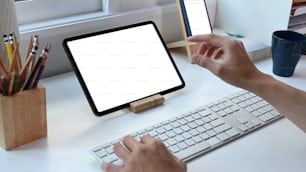 Giovane che lavora online con tablet digitale su tavolo bianco in ufficio a casa.