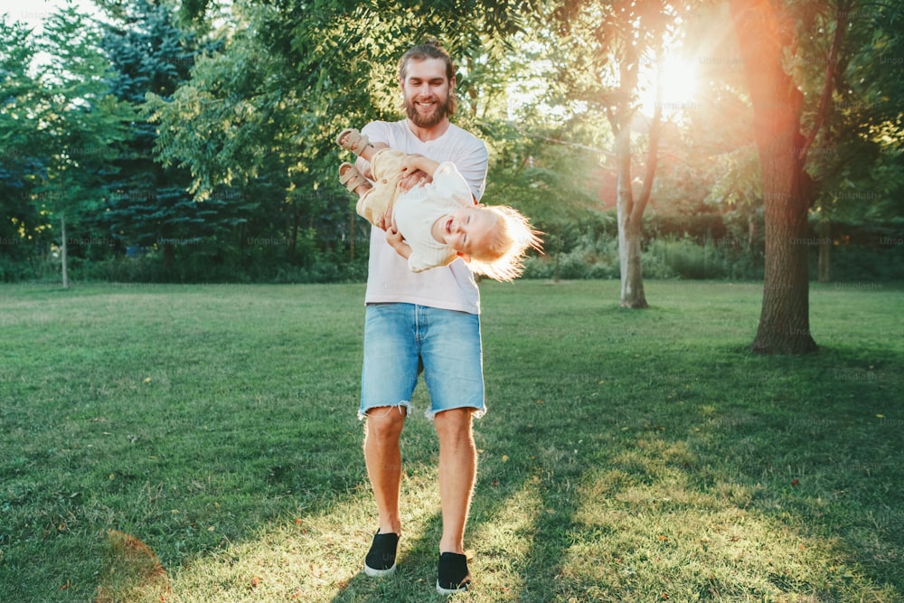 Fathers Day. Proud father spinning toddler baby boy outdoor. Parent playing with child son in park. Authentic lifestyle funny moment. Happy dad family life concept. Childhood and fatherhood.