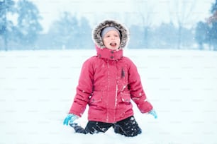 Süßes entzückendes lustiges kaukasisches aufgeregtes Kind, das während des kalten Wintertages Schnee leckt. Kinder im Freien saisonale Aktivitäten. Fröhlicher, authentischer Lebensstil in der Kindheit.