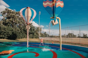 Cute adorable Caucasian funny girl playing on splash pad playground on summer day. Seasonal water sport recreational activity for kids outdoor.