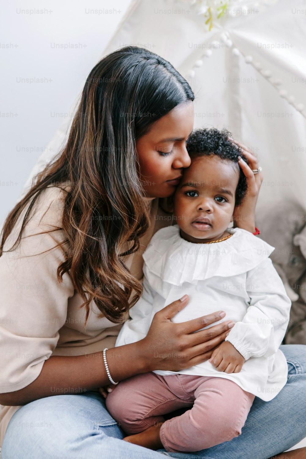 Happy young Indian mother playing kissing mixed race black baby girl daughter. Family mixed race people mom and kid together hugging embracing at home. Ethnic diversity family.