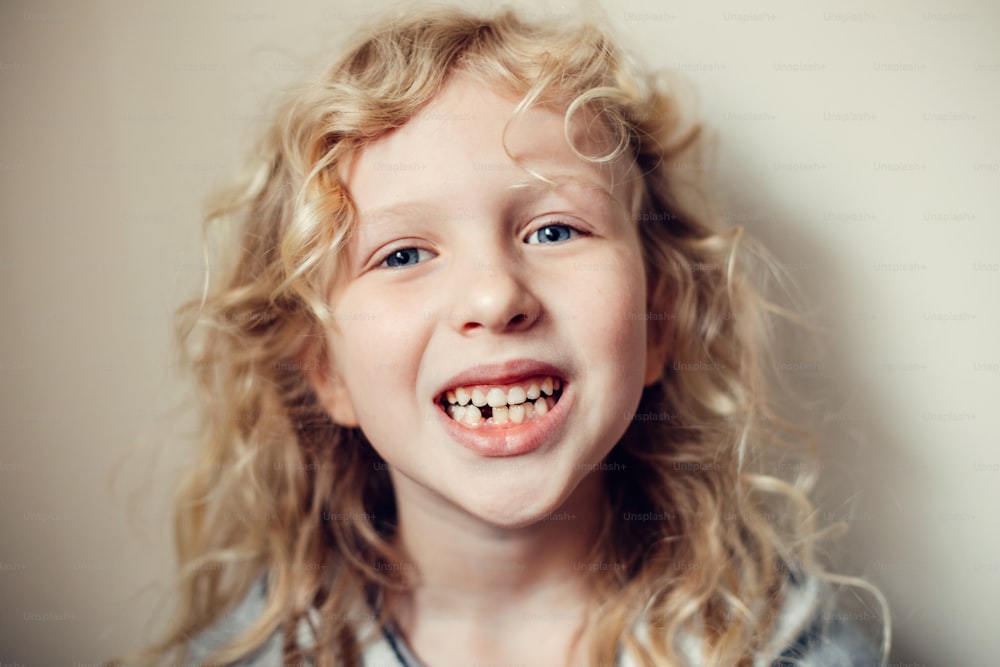笑顔の白人ブロンドの女の子の接写は、彼女の失われた乳歯を示しています。歯科口腔衛生衛生。思春期に成長する子供たちの段階。幸せな本物の子供時代のライフスタイル。