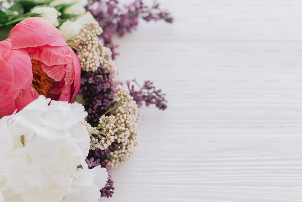 Foto Ramo elegante con flores de peonía, lilas, rosas y hortensias sobre  fondo blanco de madera con espacio para texto. Feliz día de la madre y  concepto de día de san valentín –