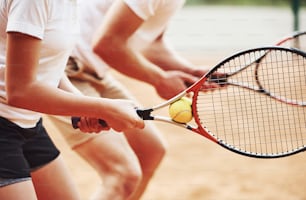 Perfil. Entrenador que enseña el juego de tenis de las estudiantes femeninas en la cancha al aire libre.