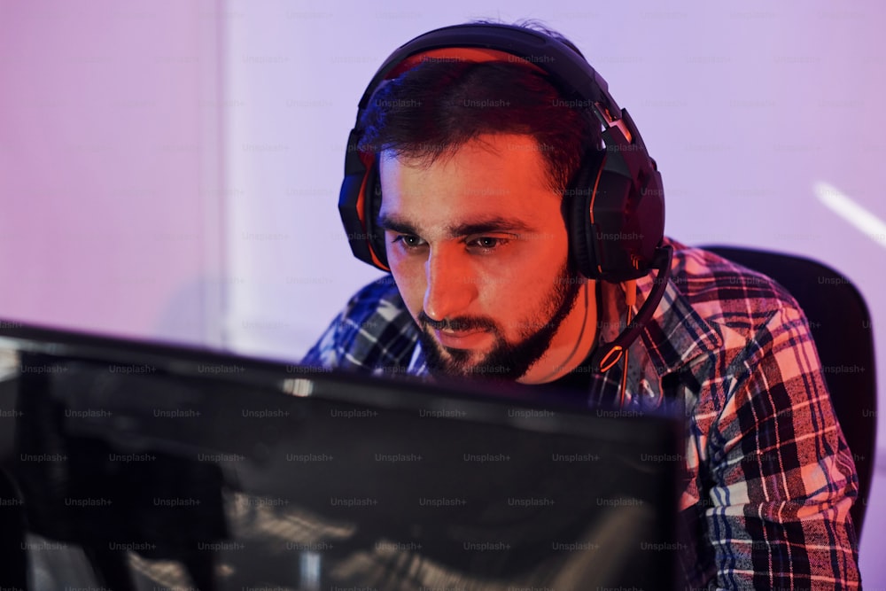 Portrait of young bearded pro gamer playing in online video game.