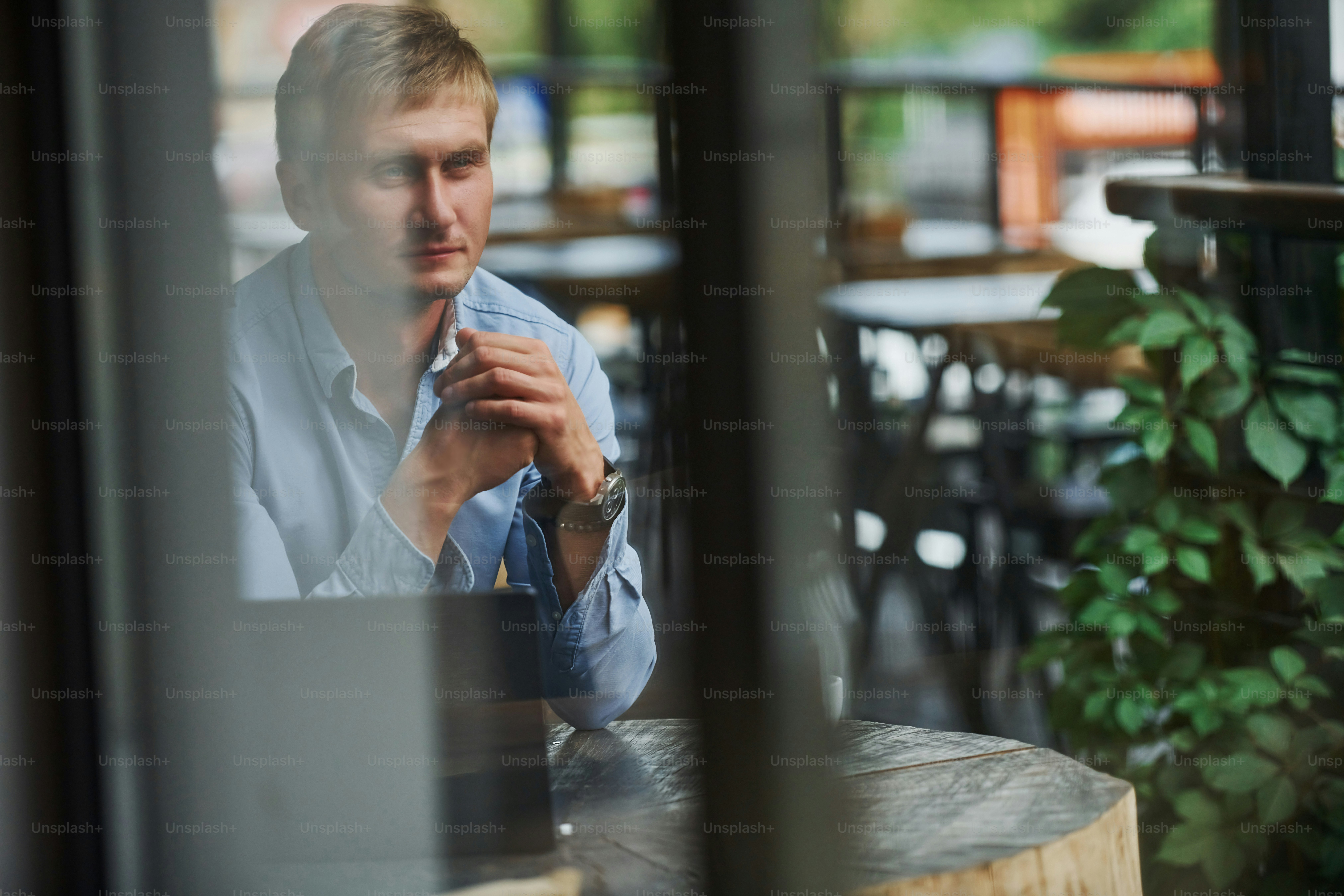 Front view of guy that is in modern cafe with his laptop at daytime.