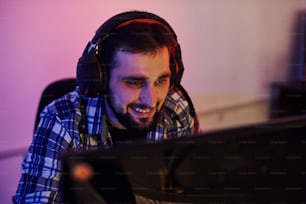 Smiling during the process. Portrait of young bearded pro gamer playing in online video game.