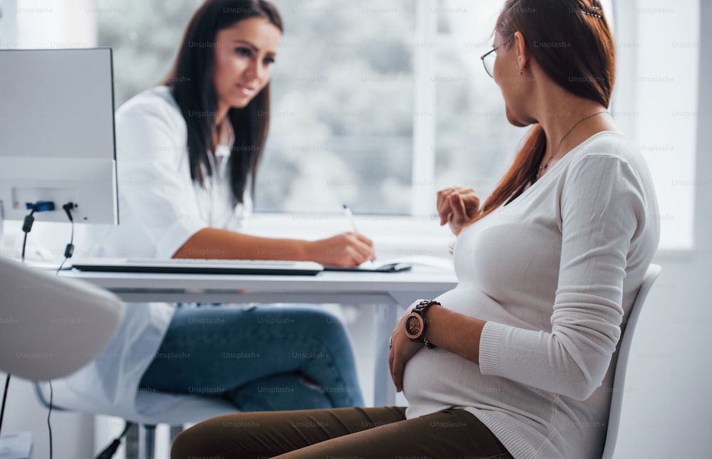Active conversation. Pregnant woman have consultation with obstetrician indoors.