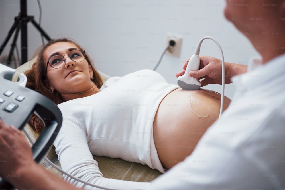 Médico do sexo masculino faz ultrassom para uma mulher grávida no hospital.