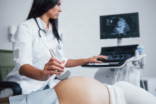 女医は病院で妊婦のために超音波検査を行います。